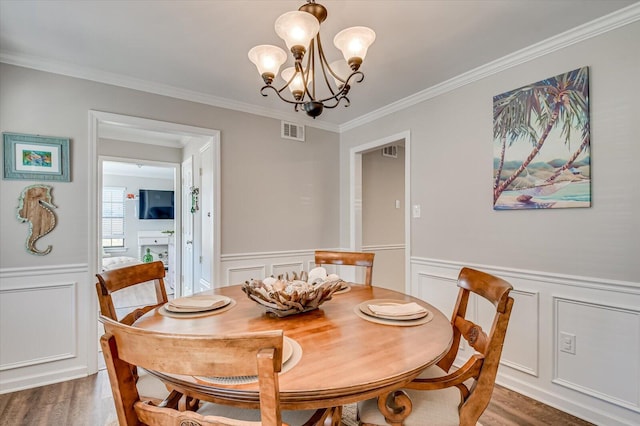 dining space with a chandelier, visible vents, wainscoting, and wood finished floors