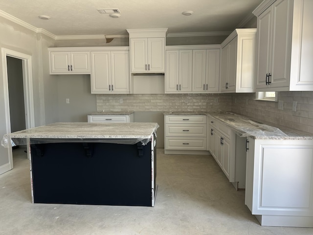 kitchen featuring crown molding, a center island, backsplash, and visible vents