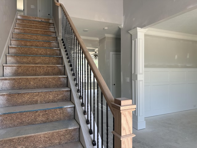 staircase with crown molding, ceiling fan, a decorative wall, and a wainscoted wall