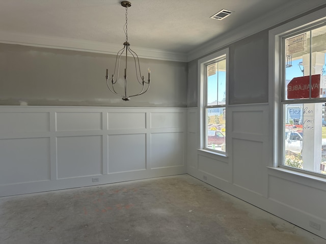 unfurnished dining area with visible vents, crown molding, a decorative wall, a chandelier, and unfinished concrete flooring