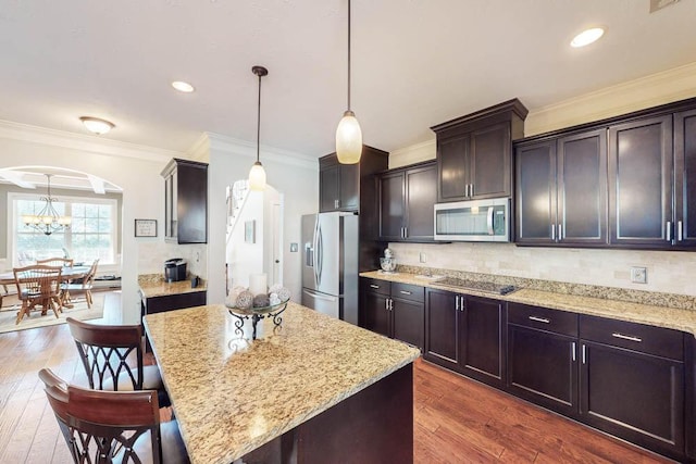 kitchen featuring dark wood-type flooring, stainless steel appliances, crown molding, and decorative light fixtures