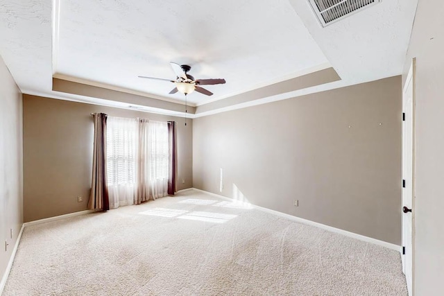 carpeted empty room with ceiling fan, a tray ceiling, and ornamental molding