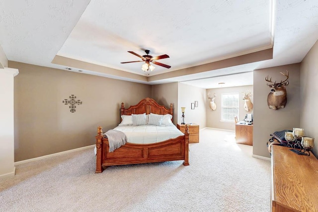 carpeted bedroom featuring ceiling fan, crown molding, and a raised ceiling