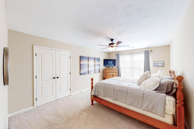 carpeted bedroom with ceiling fan, a closet, and a textured ceiling