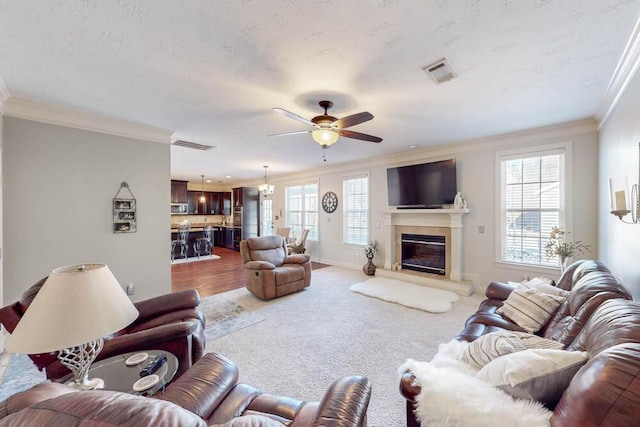 living room with ceiling fan, ornamental molding, and carpet