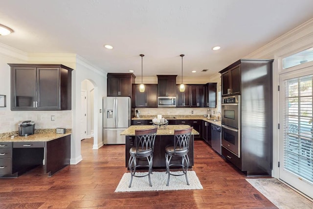 kitchen with a kitchen island, pendant lighting, light stone countertops, stainless steel appliances, and dark brown cabinets