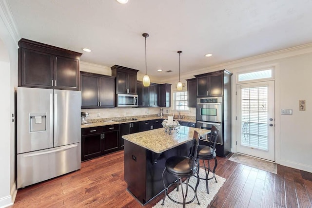 kitchen featuring pendant lighting, a center island, appliances with stainless steel finishes, a breakfast bar area, and light stone counters