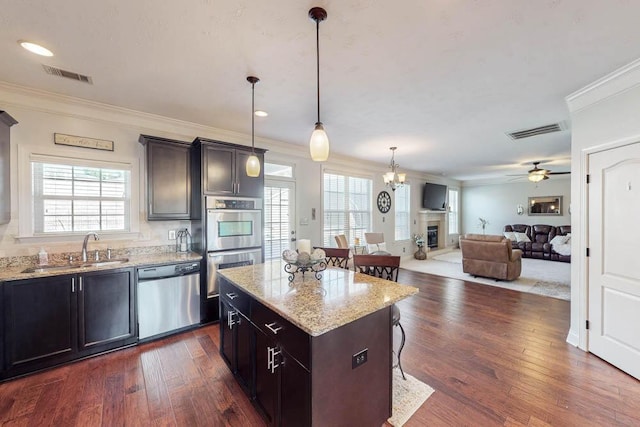 kitchen featuring pendant lighting, a kitchen island, sink, stainless steel appliances, and ceiling fan with notable chandelier