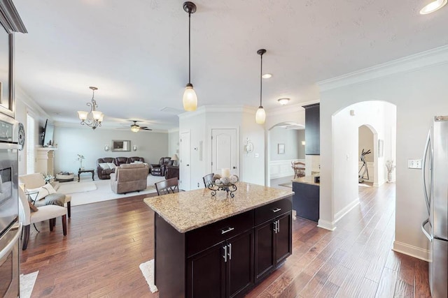 kitchen with ceiling fan with notable chandelier, a center island, decorative light fixtures, stainless steel fridge, and ornamental molding