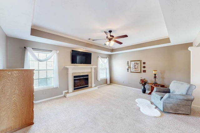 living area featuring light carpet, ceiling fan, crown molding, and a raised ceiling