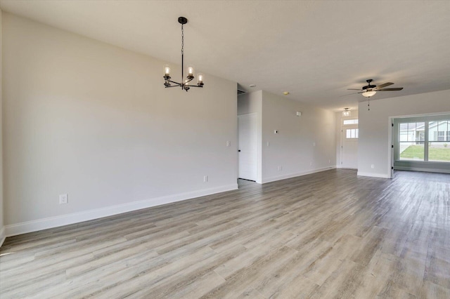 empty room featuring ceiling fan with notable chandelier and light hardwood / wood-style floors