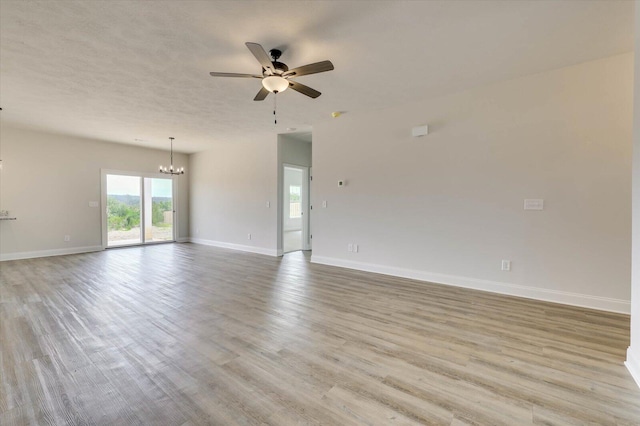 spare room featuring ceiling fan with notable chandelier and light hardwood / wood-style flooring