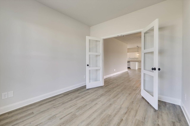 unfurnished room featuring french doors and light hardwood / wood-style flooring