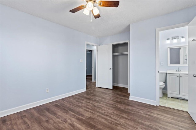 unfurnished bedroom with connected bathroom, a closet, ceiling fan, dark hardwood / wood-style floors, and sink