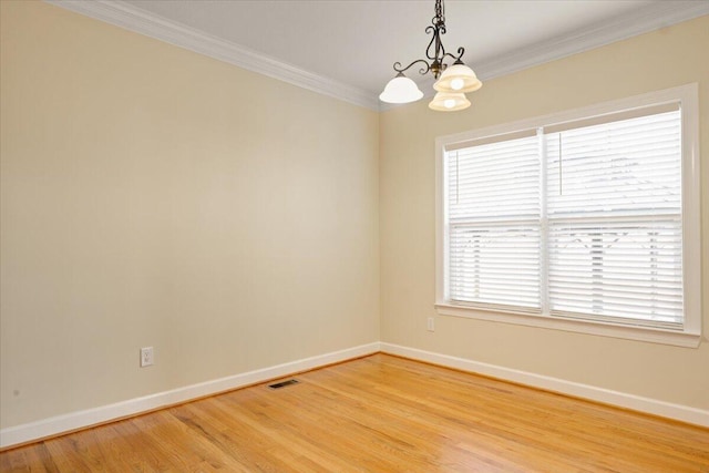 empty room with hardwood / wood-style flooring, crown molding, and a chandelier