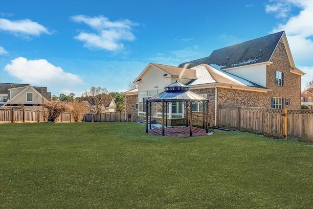 rear view of house featuring a gazebo and a yard