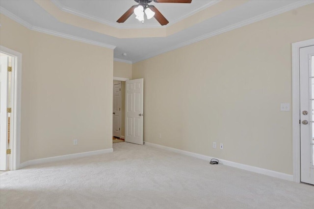 carpeted empty room featuring crown molding, ceiling fan, and a raised ceiling