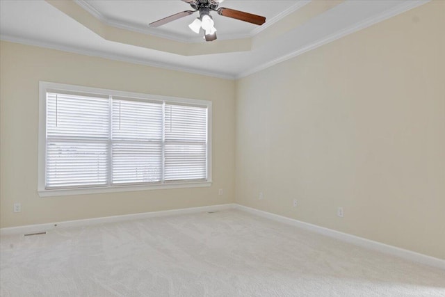 carpeted spare room featuring a raised ceiling, ornamental molding, and ceiling fan