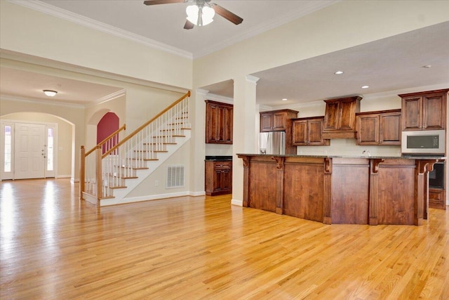 kitchen with crown molding, a kitchen breakfast bar, and light hardwood / wood-style flooring