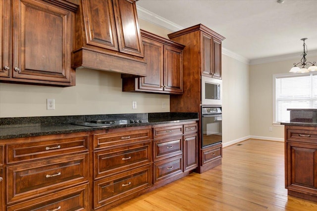 kitchen featuring ornamental molding, black appliances, dark stone counters, a chandelier, and light wood-type flooring