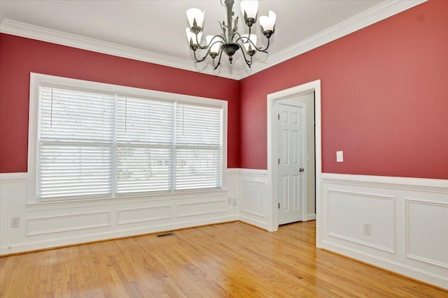 unfurnished room featuring crown molding, hardwood / wood-style floors, and a notable chandelier