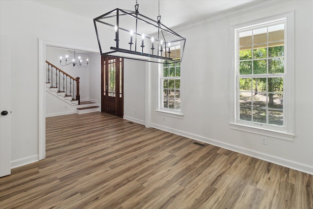 unfurnished dining area featuring stairway, wood finished floors, an inviting chandelier, and ornamental molding