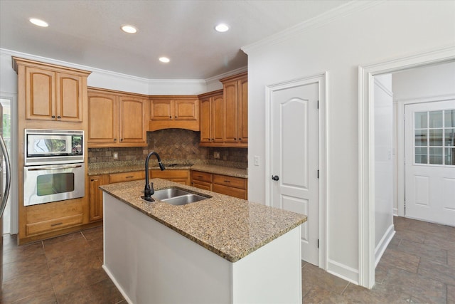 kitchen featuring light stone counters, decorative backsplash, a sink, stainless steel appliances, and a center island with sink