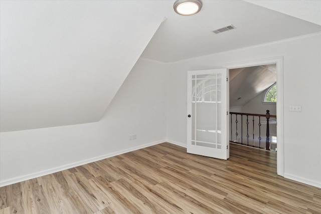 bonus room with baseboards, visible vents, light wood-type flooring, and vaulted ceiling