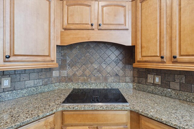 kitchen featuring light stone counters, decorative backsplash, and black electric stovetop