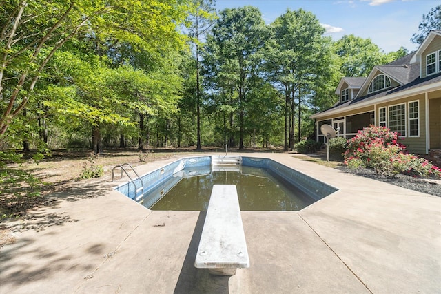 outdoor pool with a diving board and a patio