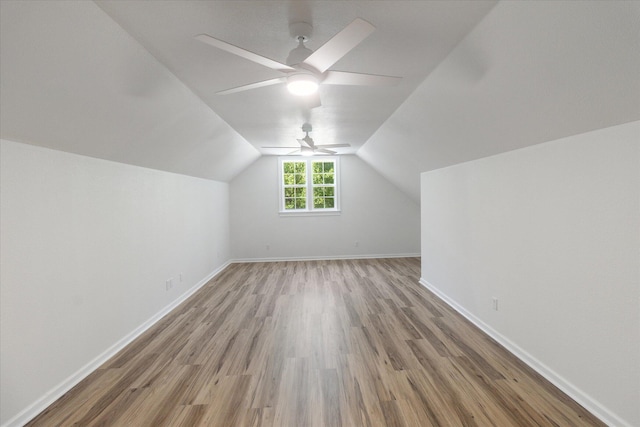 additional living space with lofted ceiling, light wood-type flooring, a ceiling fan, and baseboards