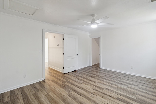 spare room featuring baseboards, light wood-type flooring, ornamental molding, and ceiling fan