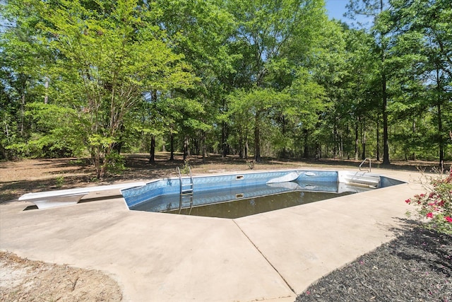 view of swimming pool featuring a diving board, an empty pool, and a patio