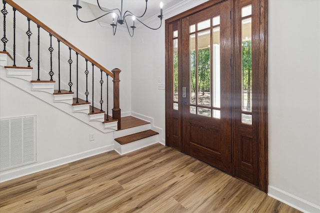 foyer entrance with stairs, visible vents, wood finished floors, and a chandelier