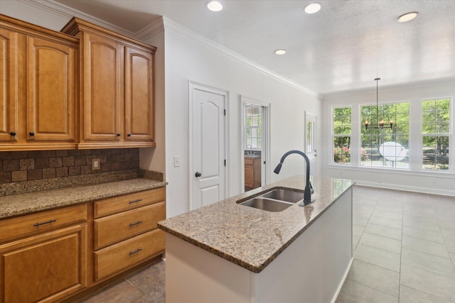 kitchen featuring brown cabinets, a sink, tasteful backsplash, light stone counters, and ornamental molding