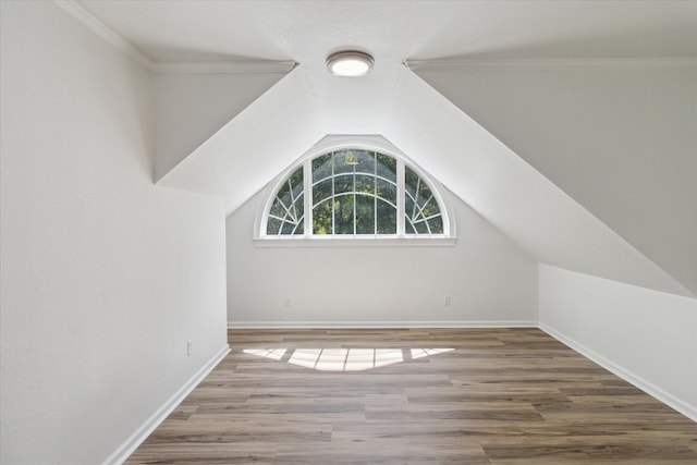 additional living space with baseboards, wood finished floors, and vaulted ceiling