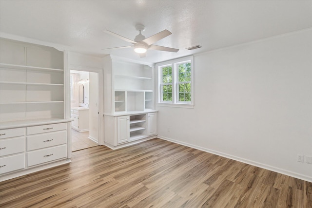 interior space featuring visible vents, baseboards, ornamental molding, light wood finished floors, and a ceiling fan