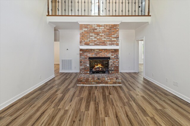 unfurnished living room with wood finished floors, visible vents, ornamental molding, and baseboards