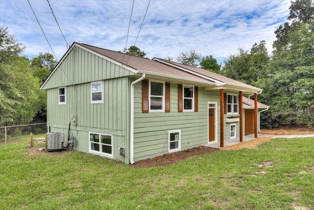 back of property featuring central air condition unit and a yard