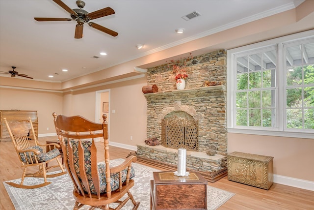 living area with crown molding, ceiling fan, baseboards, and wood finished floors