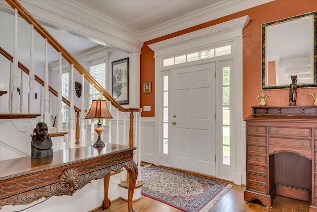 foyer with crown molding, stairway, and wood finished floors