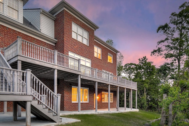 rear view of house featuring brick siding, a wooden deck, and stairway