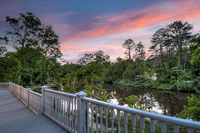 deck at dusk featuring a water view