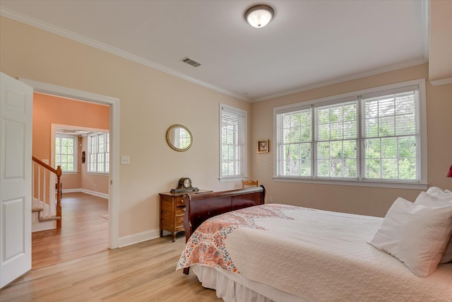 bedroom with baseboards, ornamental molding, light wood-type flooring, and visible vents