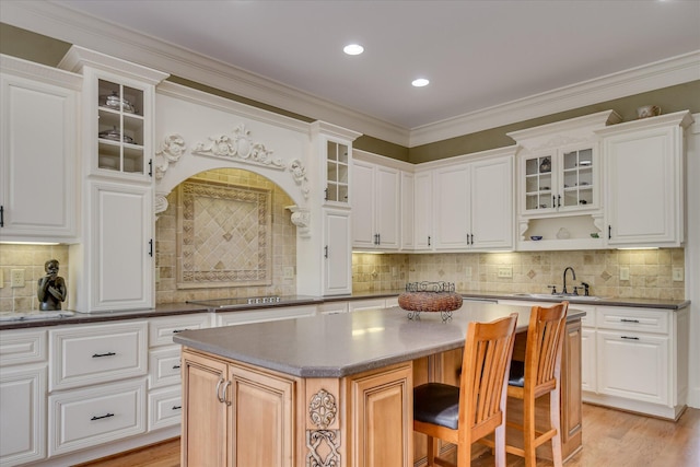 kitchen with a sink, a breakfast bar, backsplash, and a kitchen island