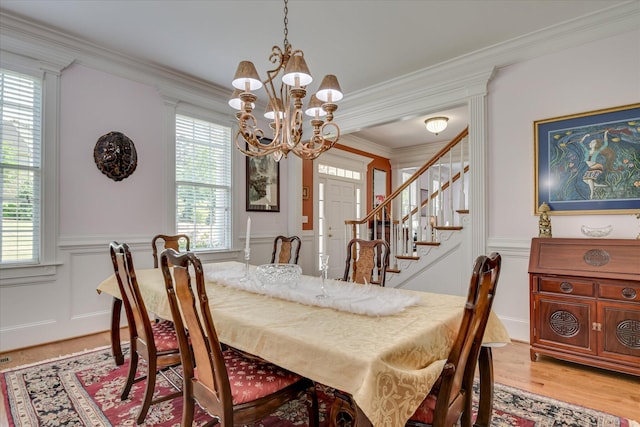 dining area with a healthy amount of sunlight, ornamental molding, wainscoting, and a chandelier