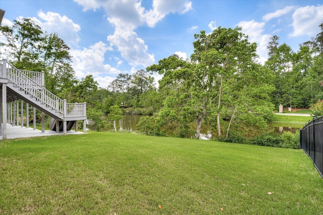 view of yard with fence, a water view, and stairway