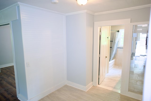 hall with baseboards, ornamental molding, and light wood-style flooring