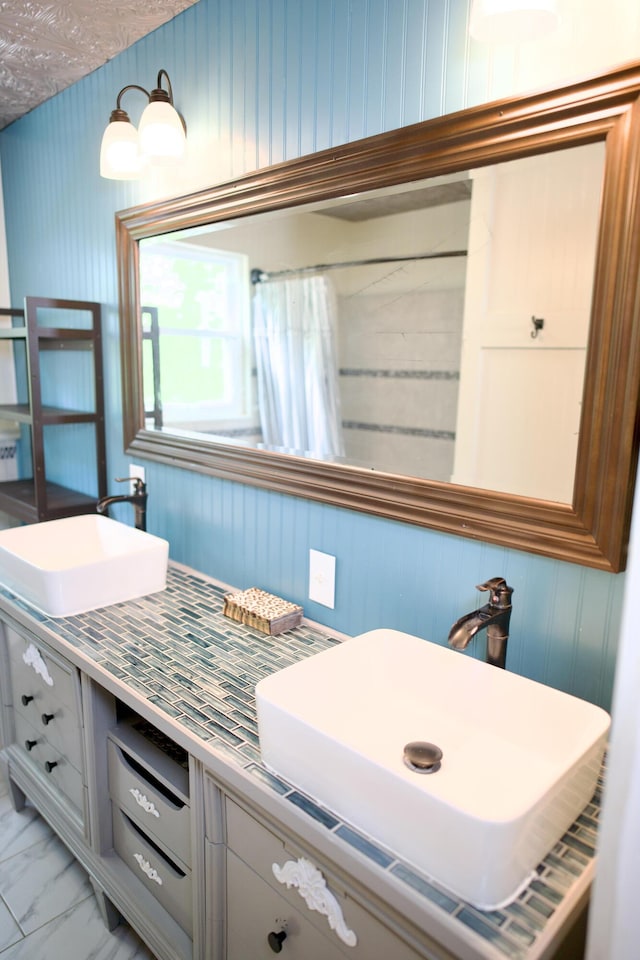 full bath featuring vanity, wood walls, marble finish floor, and a shower with curtain