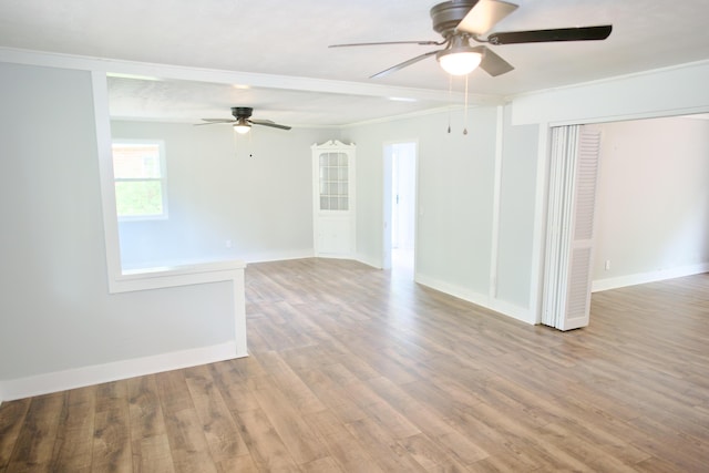 empty room featuring crown molding, a ceiling fan, baseboards, and wood finished floors